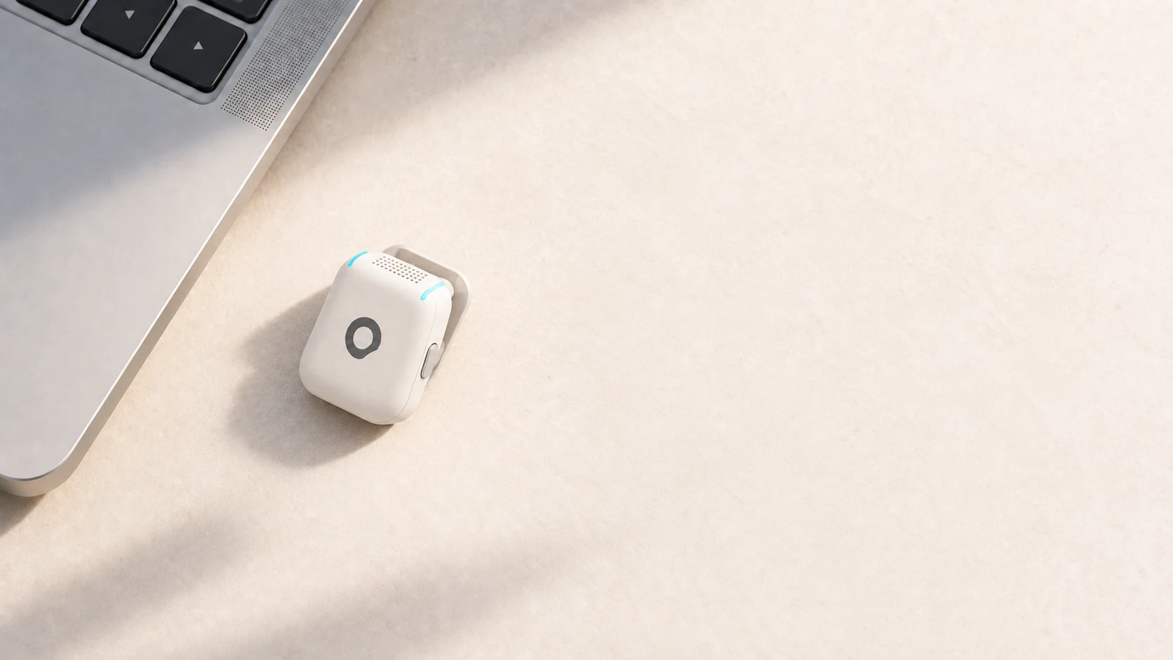 A white AERA microphone beside a silver laptop